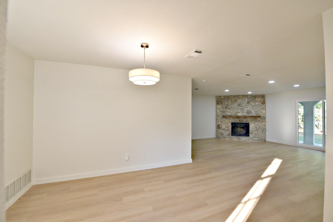 4617 Sidereal Drive Austin, TX 78727 - Photo 4 of 23 an empty room with wooden floor fireplace and windows