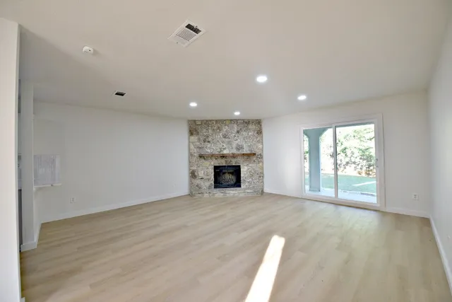 a view of an empty room with a window and fireplace