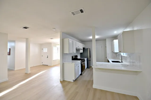 a large kitchen with a counter space a sink and stainless steel appliances