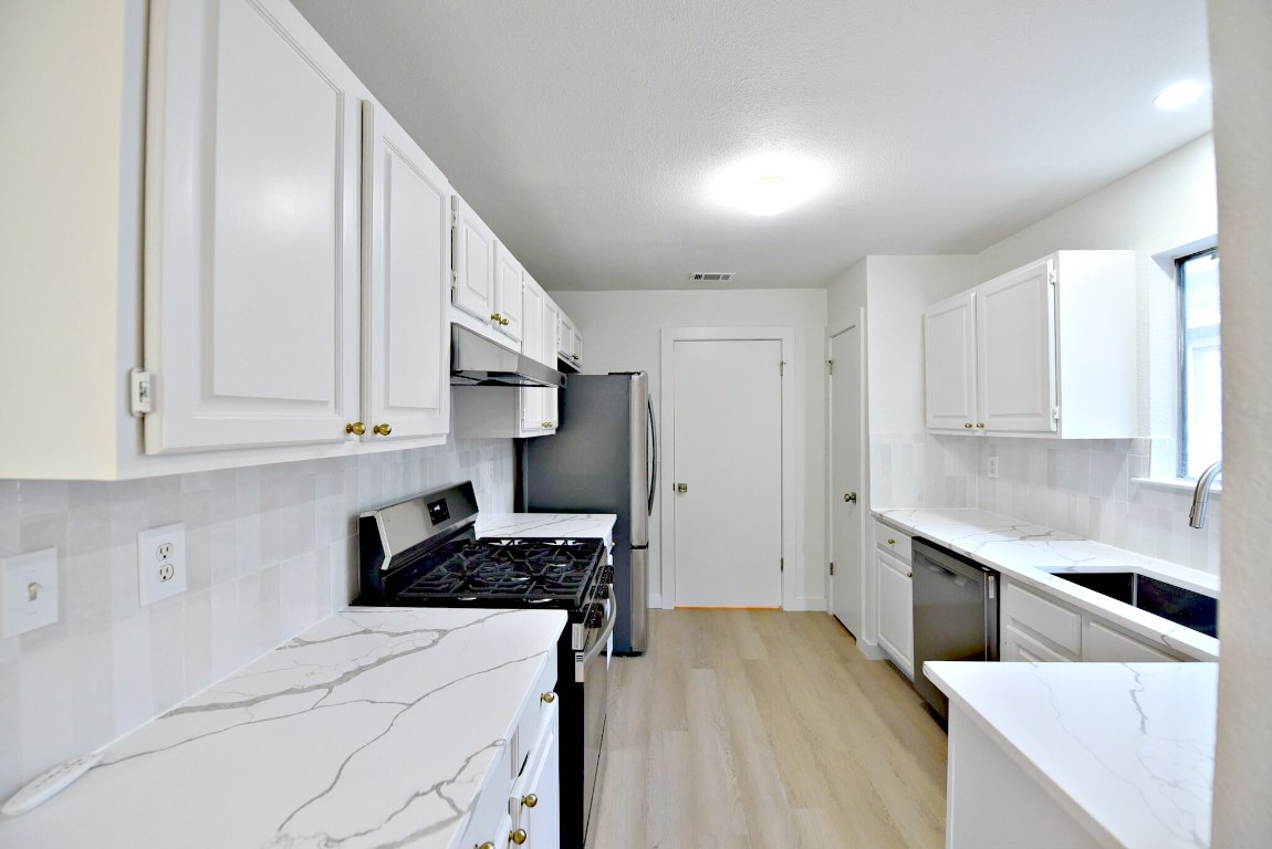 4617 Sidereal Drive Austin, TX 78727 - Photo 10 of 23 a kitchen with stainless steel appliances a stove a sink and white cabinets