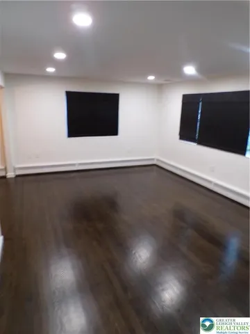 a view of an empty room with wooden floor and windows