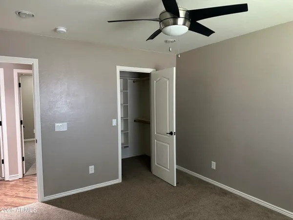 an empty room with closet and a ceiling fan
