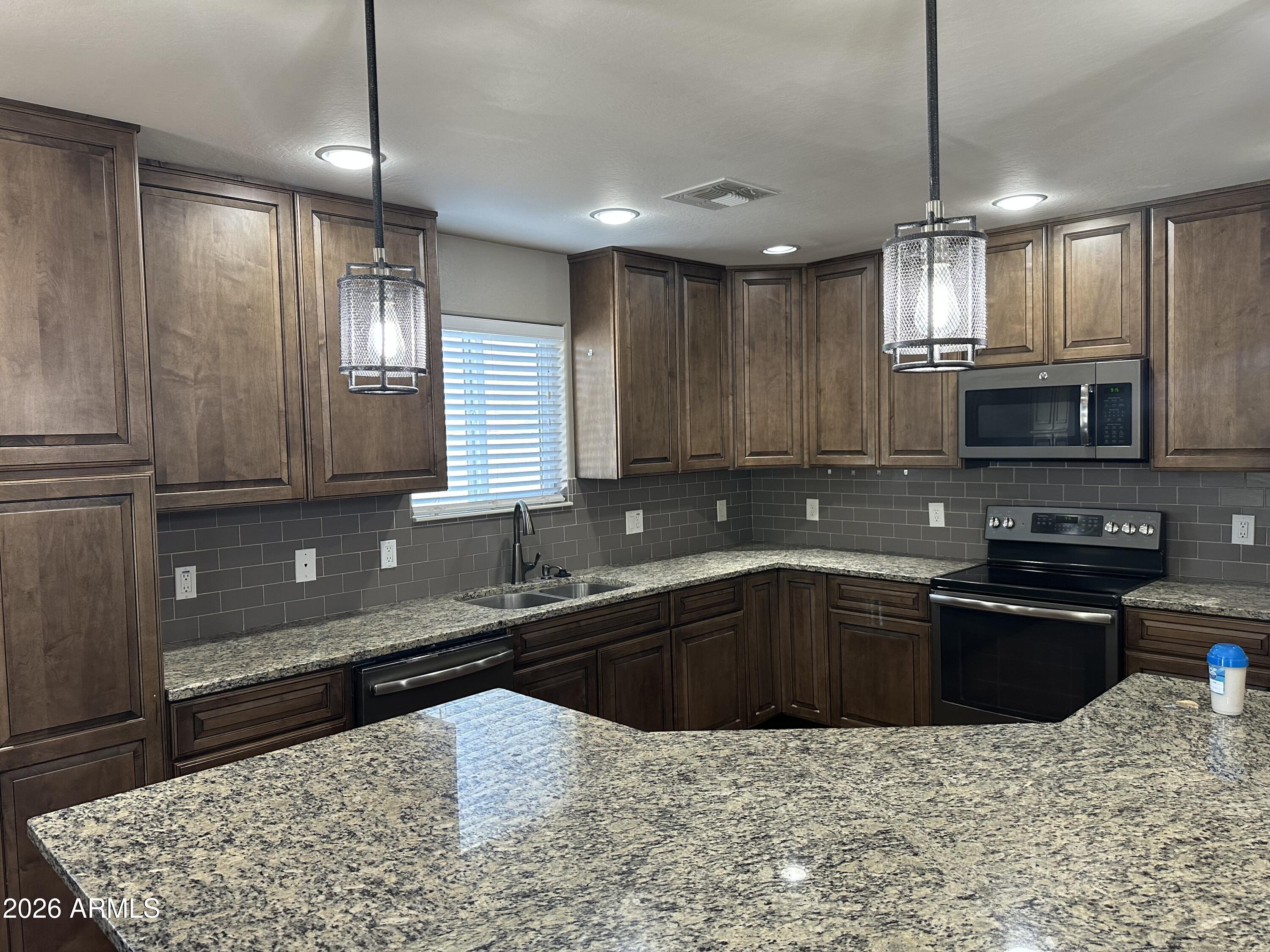 1059 West 5th Avenue Apache Junction, AZ 85120 - Photo 2 of 14 a kitchen with stainless steel appliances granite countertop a sink a stove a microwave oven and a refrigerator with wooden floor