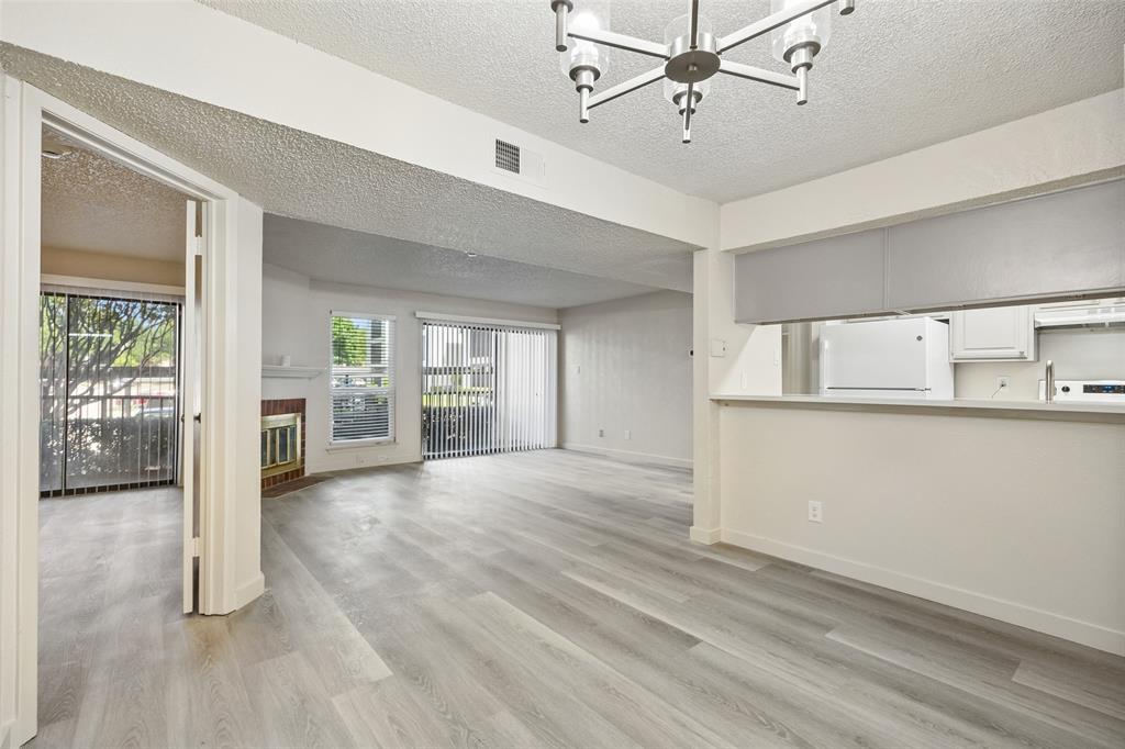 11480 Audelia Road, Unit 136 Dallas, TX 75243 - Photo 9 of 29 Living area featuring wood-finish flooring, a fireplace with a brick surround, and multiple sliding glass doors