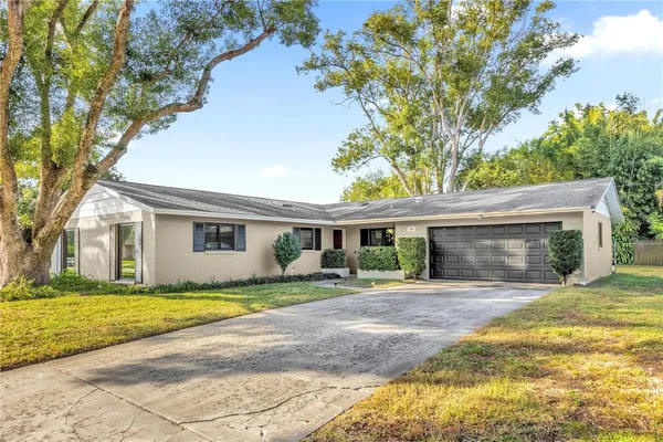a view of a house with a yard and large trees