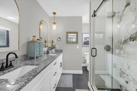 a bathroom with a granite countertop sink a mirror and shower