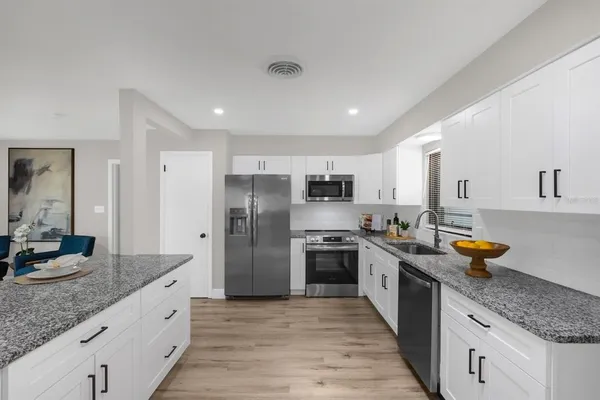a large kitchen with stainless steel appliances granite countertop a lot of counter space and wooden floors