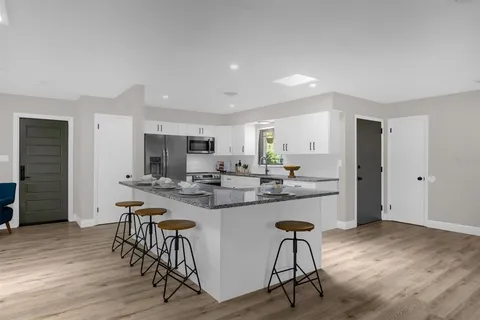 a kitchen with stainless steel appliances a dining table chairs and wooden floor