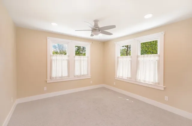 an empty room with windows and ceiling fan