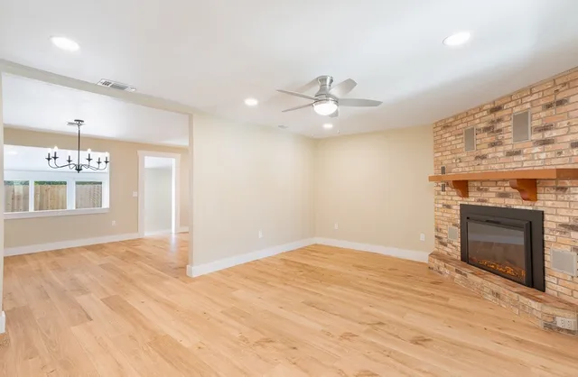 an empty room with a fireplace and chandelier fan