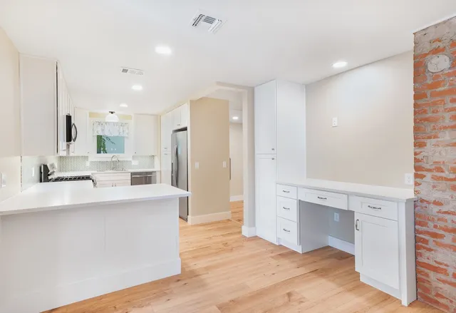 a large white kitchen with a sink and dishwasher a refrigerator with wooden floor