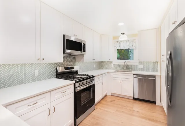 a kitchen with cabinets stainless steel appliances and wooden floor
