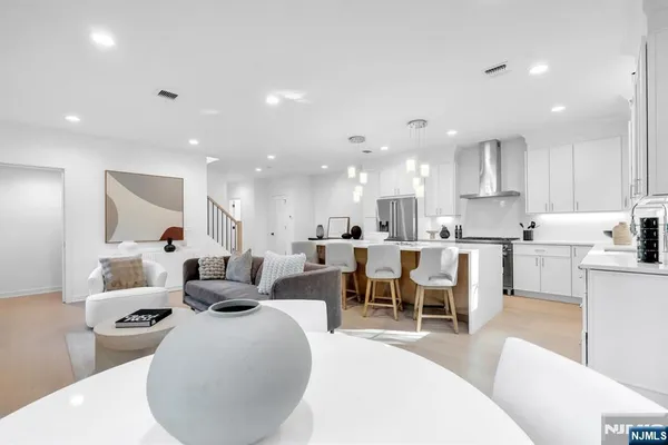 a living room with lots of white furniture and a wooden floor