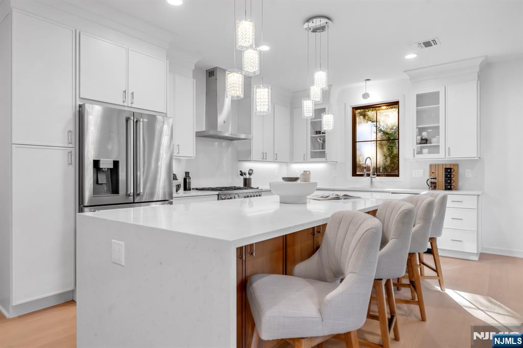 23 Fey Place Oradell, NJ 07649 - Photo 5 of 36 a kitchen with stainless steel appliances granite countertop a sink a stove a refrigerator a microwave and white cabinets with wooden floor