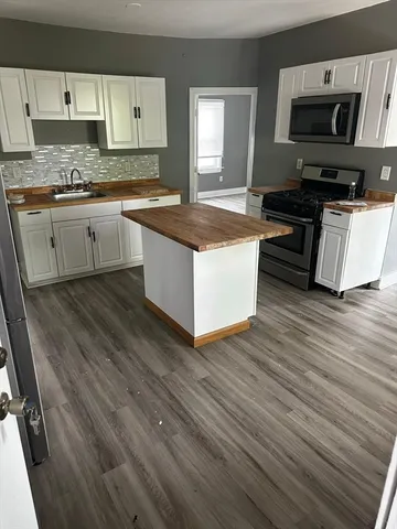 a kitchen with granite countertop a sink cabinets and wooden floor