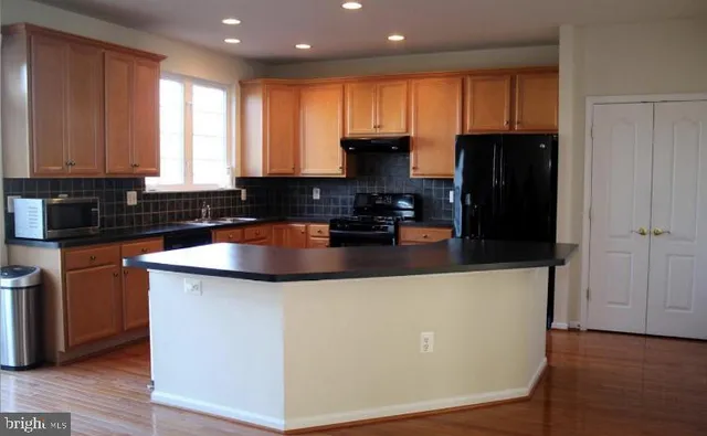 a kitchen with granite countertop a refrigerator a sink and wooden cabinets