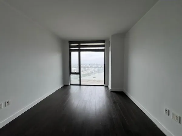 an empty room with wooden floor and windows