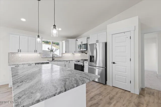 a view of a kitchen with a stove a refrigerator and cabinets