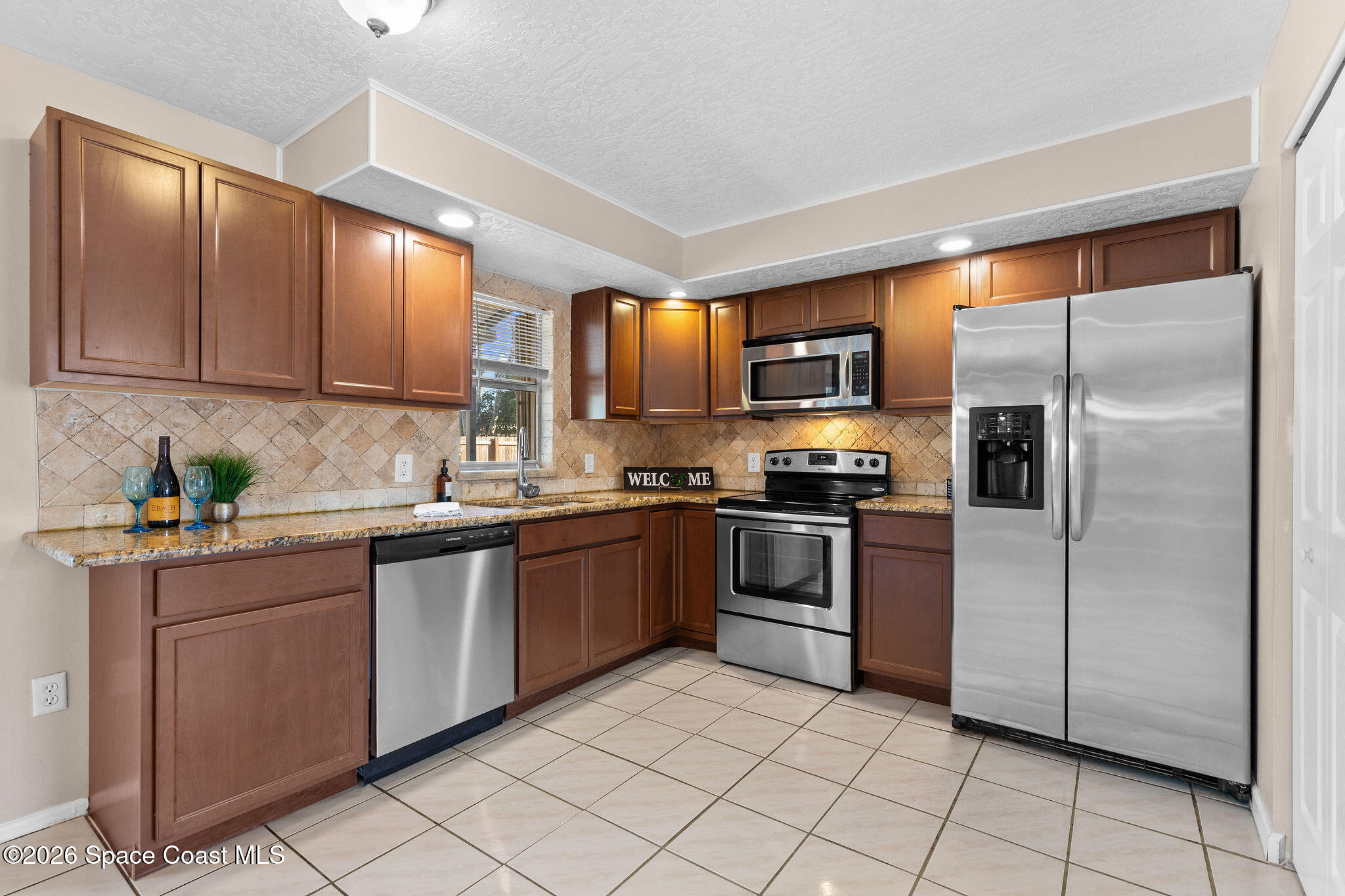 998 Kings Post Road Rockledge, FL 32955 - Photo 27 of 39 a kitchen with granite countertop stainless steel appliances a refrigerator sink and microwave