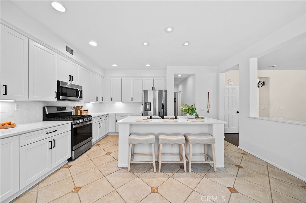 29027 Raintree Lane Saugus, CA 91390 - Photo 18 of 44 a kitchen with stainless steel appliances kitchen island granite countertop a stove a sink a microwave a dining table and chairs