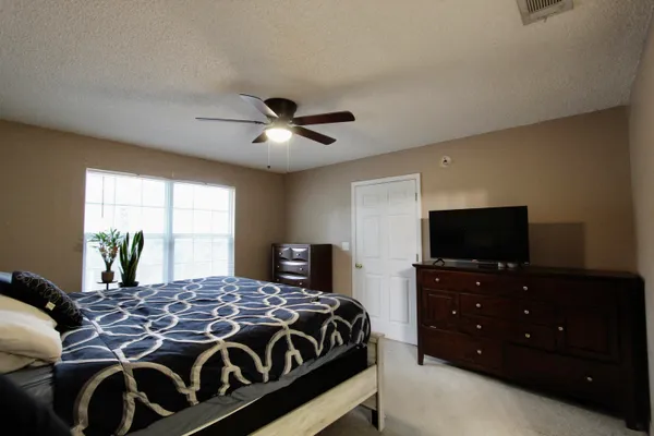 a bedroom with a bed and a flat tv screen on dresser