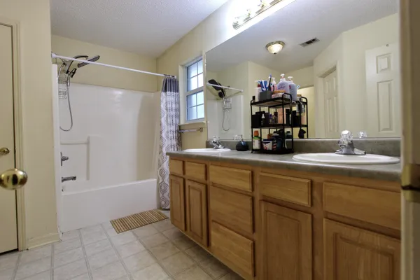 a bathroom with a double vanity sink a mirror and a bathtub