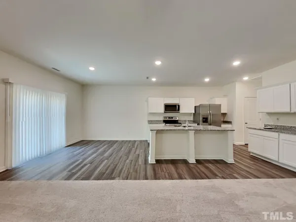 a open kitchen with kitchen island a sink dishwasher a stove and white countertops with wooden floor