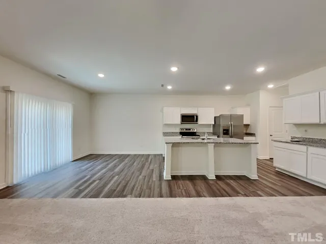 a open kitchen with kitchen island a sink dishwasher a stove and white countertops with wooden floor