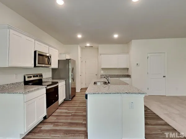 a large kitchen with granite countertop a large counter top stainless steel appliances and cabinets