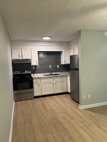 a kitchen with granite countertop a sink cabinets stainless steel appliances and a window