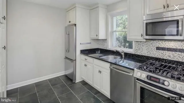 a kitchen with granite countertop a sink stove and microwave