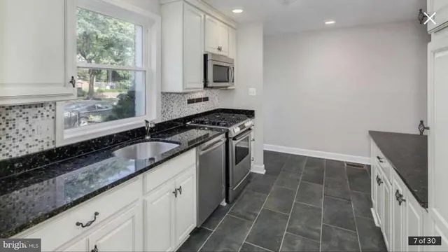 a kitchen with granite countertop a sink a stove and cabinets