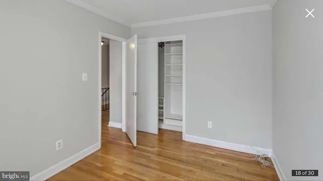 a view of an empty room with wooden floor and closet