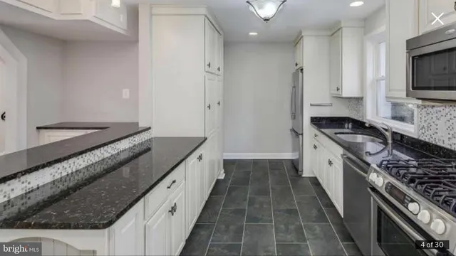a kitchen with granite countertop a sink stove and refrigerator