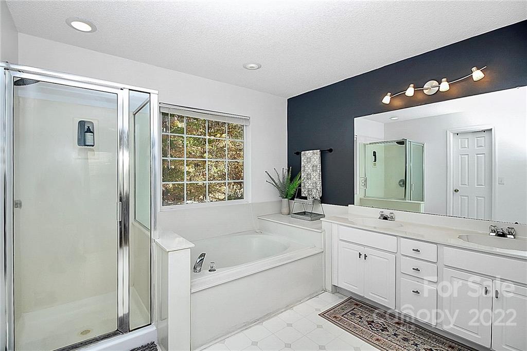 12403 Old Timber Road Charlotte, NC 28269 - Photo 18 of 33 a bathroom with a bathtub a double vanity sink and a large mirror