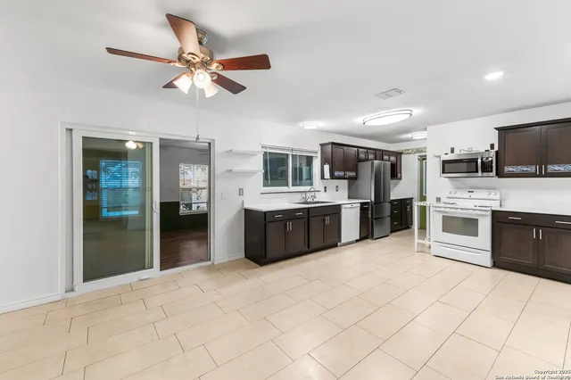a large kitchen with stainless steel appliances kitchen island granite countertop a refrigerator and a sink