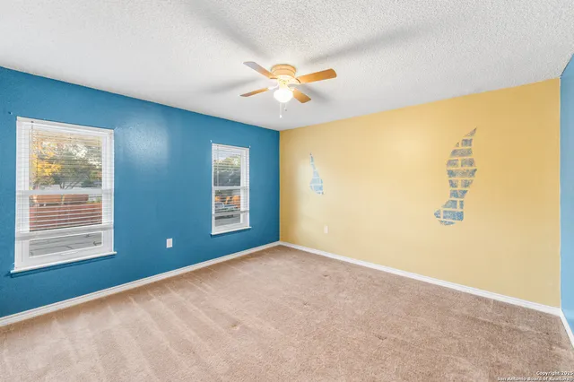 a view of an empty room with window and chandelier fan