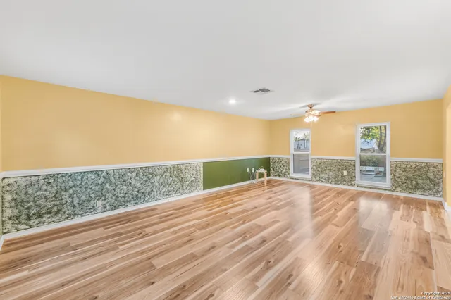 a view of an empty room with wooden floor and a window