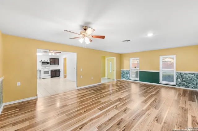 a view of an empty room with a window and wooden floor