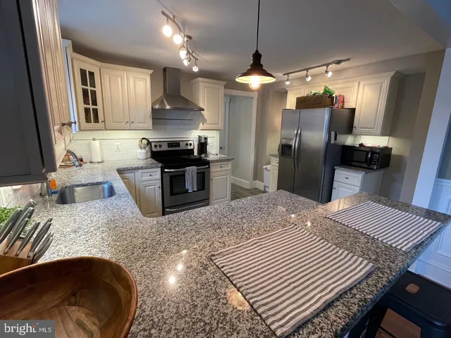 a kitchen with stainless steel appliances granite countertop a sink refrigerator and cabinets