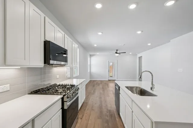 a kitchen with a sink stove top oven and cabinets