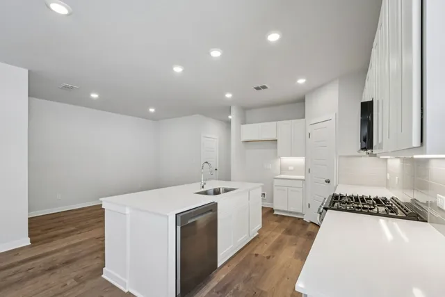 a kitchen with a sink a stove a refrigerator and white cabinets