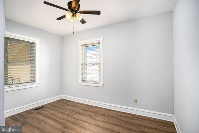 a view of an empty room with window and wooden floor