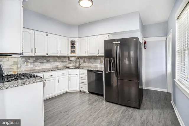 a kitchen with granite countertop a refrigerator and a stove top oven