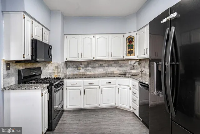 a kitchen with stainless steel appliances granite countertop a stove top oven a refrigerator and white cabinets