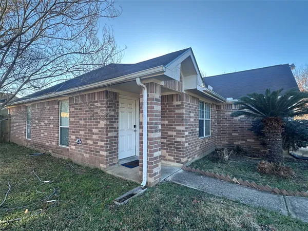 a brick house with a small yard and large trees
