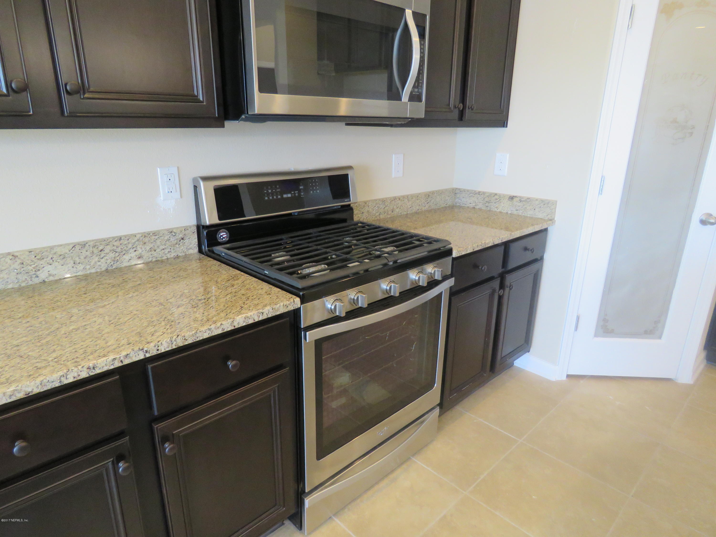 516 Deer Crossing Road St. Augustine, FL 32086 - Photo 19 of 43 a kitchen with granite countertop cabinets stove top oven and microwave