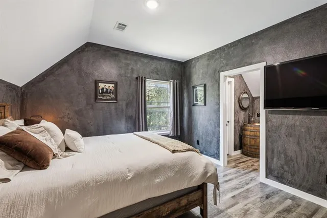 a bedroom with a large bed and a flat tv screen