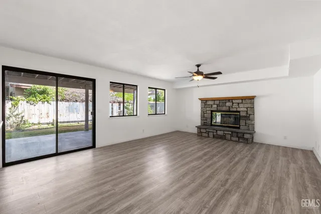 an empty room with fireplace wooden floor and windows