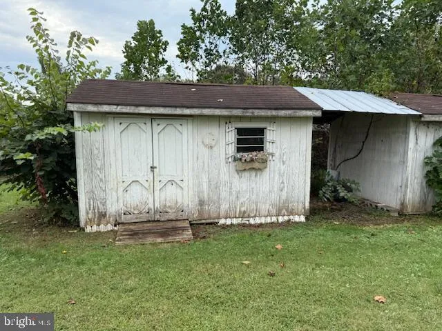 a backyard of a house with table and chairs under an umbrella